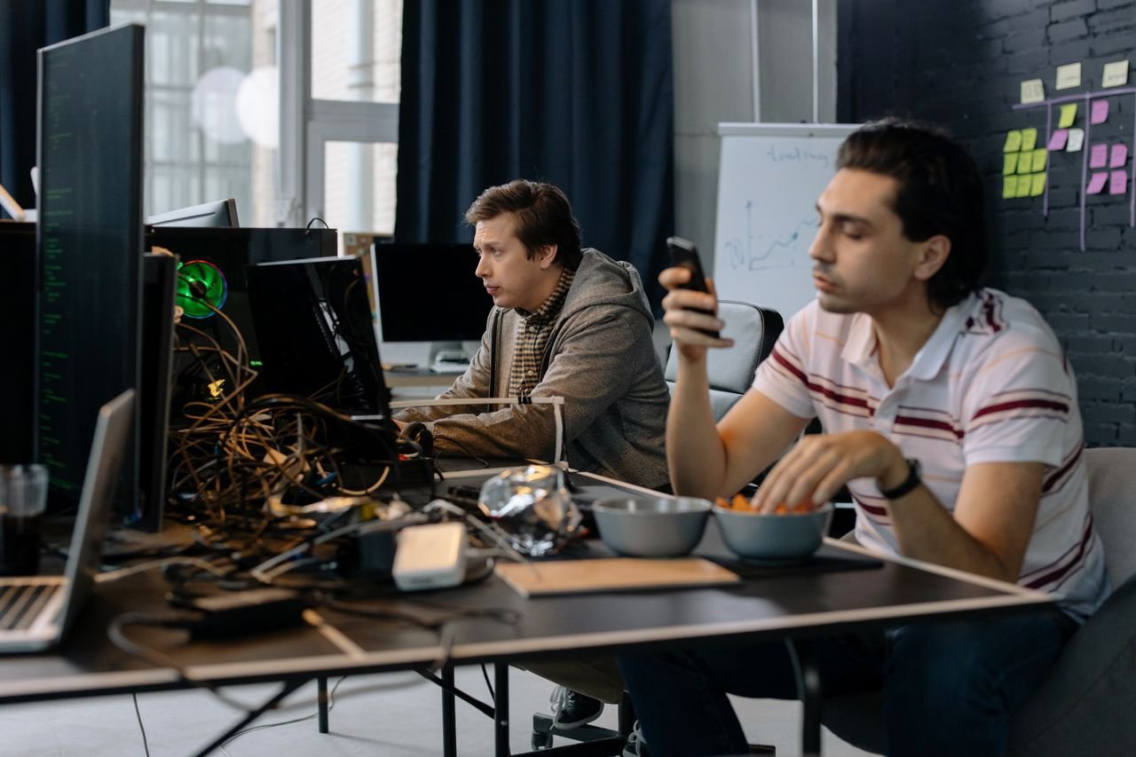 Two men working in a modern office setup, focused on technology and collaboration.